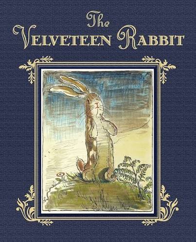 Book cover for The Velveteen Rabbit featuring a framed illustration of a standing rabbit on grass against a blue textured background with decorative gold borders
